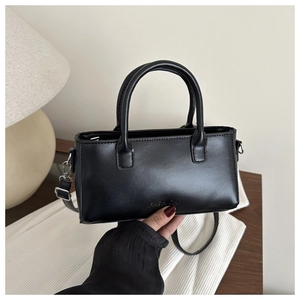 Detail of a black leather square handbag with FASHION lettering and detachable strap
