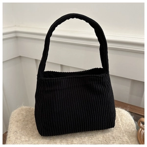 Detail of black corduroy shoulder bag with vertical ribbed texture on soft fabric