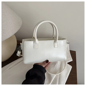 Close-up of a white leather square bag with dual handles and FASHION lettering