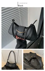 Detail of black matte underarm bag with gold metal trim and knotted strap design