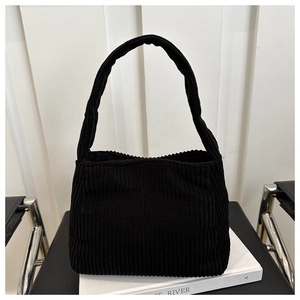Detailed view of black corduroy shoulder bag texture on minimalist modern chair