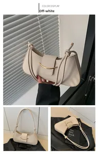Detail of off-white shoulder bag featuring a gold metal buckle and knotted strap detail