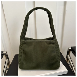 Close-up of deep green corduroy shoulder bag showing vertical rib texture and tote handle