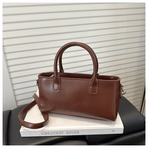 Detail of a brown PU leather crossbody bag featuring an embossed FASHION logo on white books