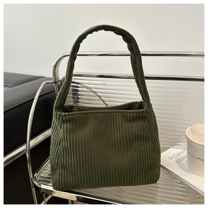 Detailed texture of dark green corduroy shoulder bag on a minimalist display stand