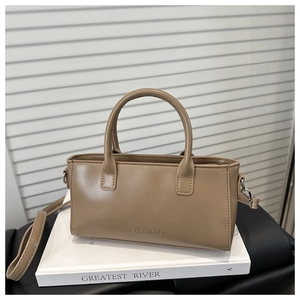 Detail view of khaki crossbody bag with Fashion logo on a white book stack
