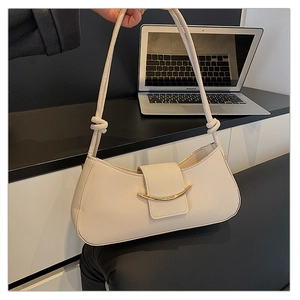 Detail of cream leather baguette bag featuring golden crescent buckle and knot strap detail