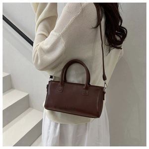 Side view of a vintage dark brown leather square crossbody bag worn by a model