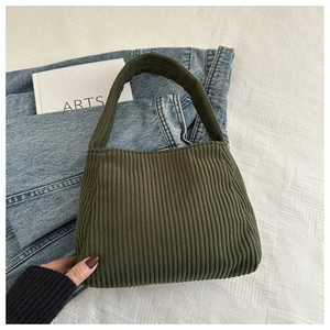 Detail of dark green corduroy tote bag showing thick striped texture on white fabric