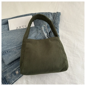 Detail of dark green corduroy shoulder bag texture placed on jeans and art book