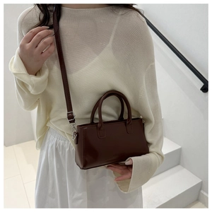 Detailed view of dark brown faux leather crossbody bag with dual handles and strap