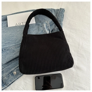 Close-up of black corduroy tote bag with textured stripes shown on denim clothing