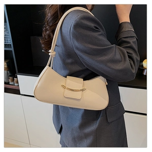 Detail of beige crescent underarm bag with gold metal buckle on a dark grey blazer