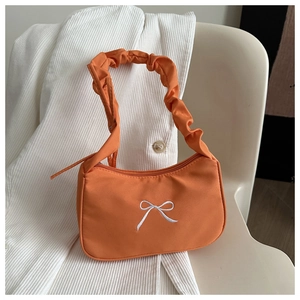 Detail of orange fabric baguette bag with white bow embroidery and scrunchie handle