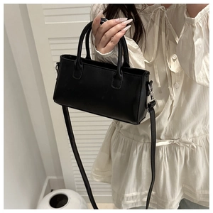 Close-up of a black square crossbody bag showing leather texture and silver hardware