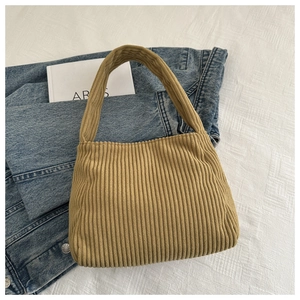Detail of camel corduroy texture and integrated handle on a minimalist shoulder bag