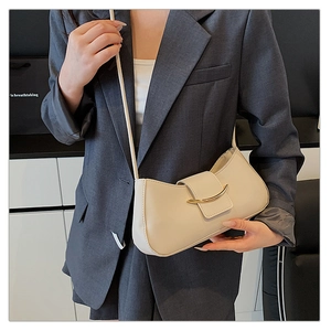 Detail of cream shoulder bag with gold clasp shown on a model in a grey blazer
