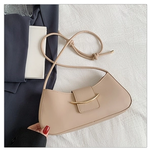 Close-up of beige leather shoulder bag featuring a gold metal clasp and knotted strap