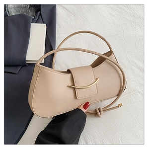 Detail of apricot shoulder bag with a curved gold clasp and minimalist leather design