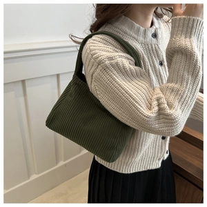 Macro view of dark green knitted tote bag showing its pleated texture and vertical stripes