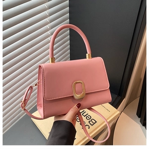 Detailed view of pink leather handbag featuring a golden oval clasp and elegant handle