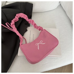 Detail of light pink shoulder bag featuring a white bow print and stylish ruched strap