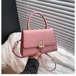 Detail of pink leather handbag featuring a golden oval clasp and detachable strap