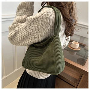 Detail of dark green corduroy shoulder bag showing vertical ribbed texture and fabric