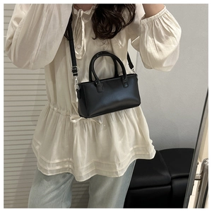 Detail shot of a black leather handbag with silver hardware and shoulder strap