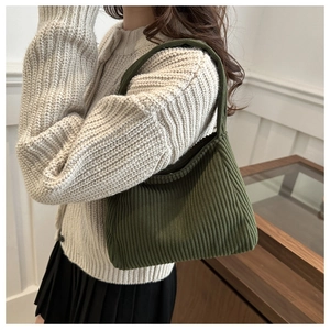 Detail of dark green ribbed knit tote bag featuring soft texture and integrated strap