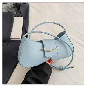 Detail of light blue leather handbag with golden crescent buckle and knot strap detail