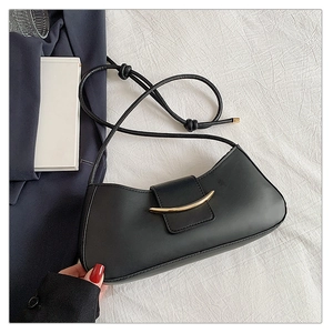Close-up of black half-moon shoulder bag with gold crescent buckle on white fabric