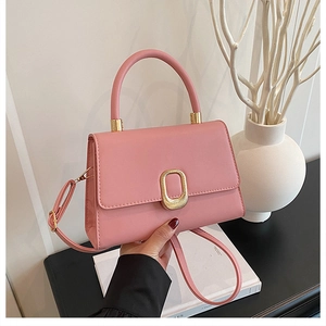 Detail of soft pink PU leather handbag with gold textured oval metal buckle and top handle