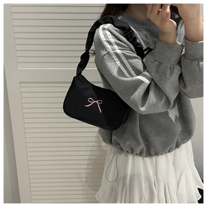 Detail of black shoulder bag with pink bow embroidery and ruffled strap design