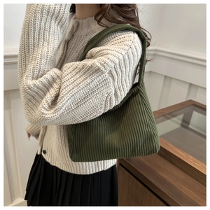 Detail shot of a dark green corduroy tote bag with vertical textured stripes on shoulder