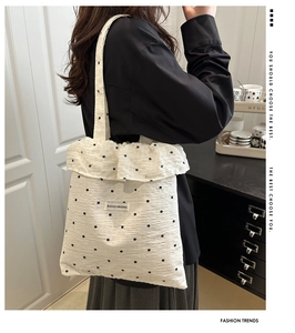 Close-up of white canvas tote bag with black floral print and stylish ruffled edge trim