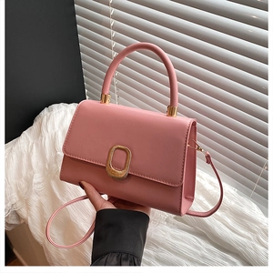 Detail of pink faux leather crossbody bag with elegant gold oval metal buckle and handle