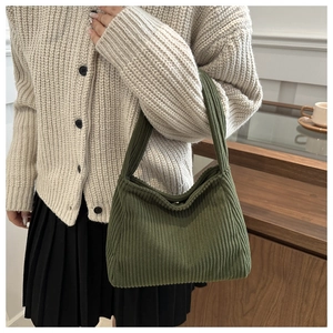 Olive green corduroy knit tote bag styled with a beige cardigan and black pleated skirt