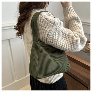 Detail of dark green corduroy shoulder bag showing vertical rib texture on shoulder strap