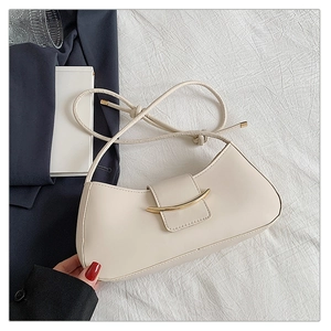 Detail view of a cream half-moon hobo bag with a gold curved buckle and knotted strap