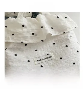 Close-up of white seersucker tote bag fabric with black floral patterns and brand label