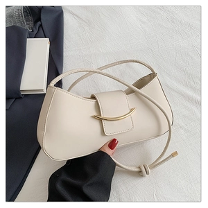 Close-up of cream leather shoulder bag featuring a gold crescent magnetic buckle closure
