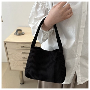 Detail of black corduroy tote bag showing soft ribbed texture and hand-held handle strap