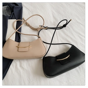 Close-up of minimalist leather shoulder bags in black and beige with gold metal bar details