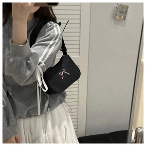 Mirror selfie showing black underarm bag with pink bow embroidery on casual outfit