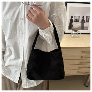Detail of black corduroy tote bag showing soft vertical ribbed texture and handheld style