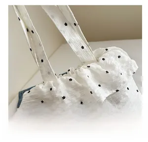 Detail of white ruffle mesh tote with black floral patterns and GOGO ORIGINAL label
