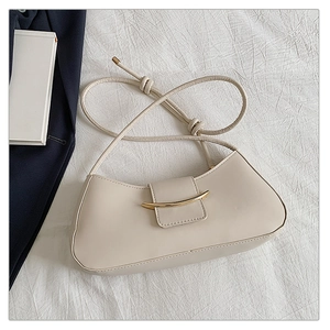 Detail of off-white baguette bag featuring a polished gold curved metal buckle and thin strap