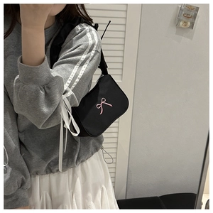 Mirror selfie showing a black nylon underarm bag with pink bow embroidery detail