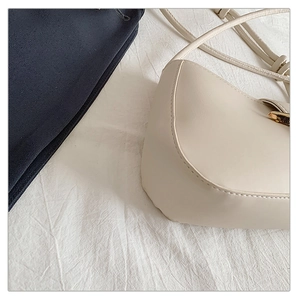 Close-up of cream leather shoulder bag featuring golden buckle and fine stitching details